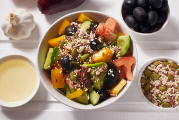 Salad of vegetables, black olives with olive oil, sprinkled with whole grains and seeds. Healthy eating.