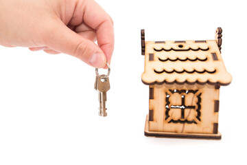 Obraz premium keys in hand and a wooden house on a white background.