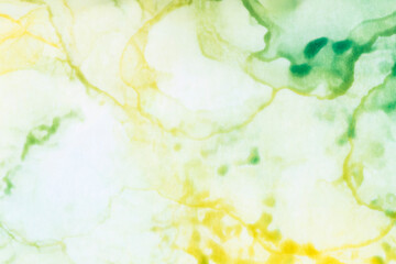 Macro close-up of blurry yellow and green alcohol ink layers and splashes, abstract background. Fluid ink, colorful full frame textured background. Vibrant color. Art for design.