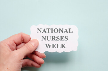 National Nurses Week medical concept on white.  Woman's hand holds a sheet of paper with text