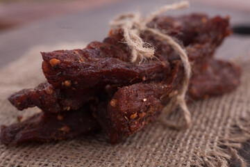 Organic Dried Pork with Pepper Dried Seal, Studio Shot. Jerky on sacking. Wooden background. 
