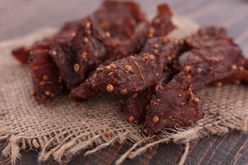 Organic Dried Pork with Pepper Dried Seal, Studio Shot. Jerky on sacking. Wooden background. 