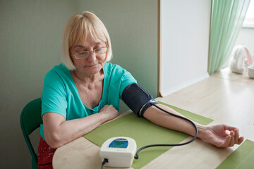 Senior adult using medical electronic device and measuring blood pressure at home, health care and treatment