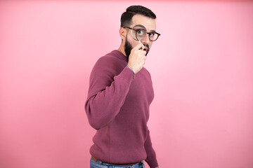 Handsome man wearing glasses and casual clothes over pink background surprised looking through a...