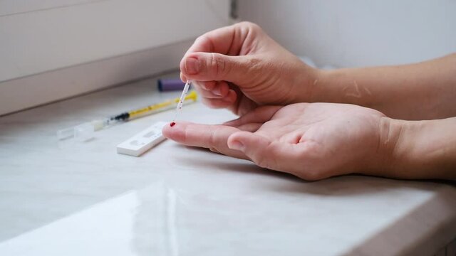 A woman doing a rapid test at home to determine the coronavirus, COVID 19. PatienCovid-19 test kit for the determination of IgM IgG antibodies and immunity in 15 minutes.