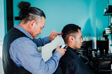 latin man stylist cutting hair to a client in a barber shop in Mexico