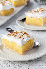 Close up of a slice of lemon meringue square ready for eating with other slices in behind.