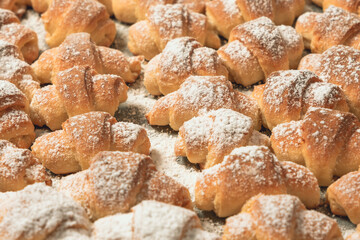 Homemade cakes, on a baking sheet fresh baked in the oven bagels made of cottage cheese dough sprinkled with powdered sugar