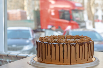delicious chocolate cake with butter cream on a table in a roadside cafe on the background of a window by the road