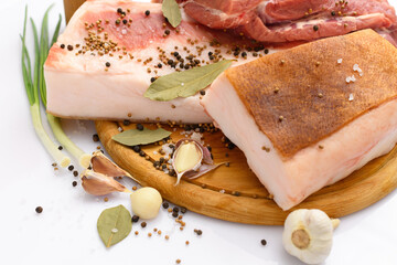 raw pork meat and lard with salt, spices and garlic on a cutting board, white background