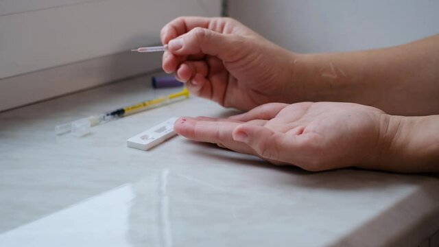 A woman doing a rapid test at home to determine the coronavirus, COVID 19. PatienCovid-19 test kit for the determination of IgM IgG antibodies and immunity in 15 minutes.