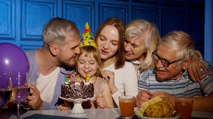 Adorable child girl kid eating cake making wish, having fun, celebrating birthday party with family