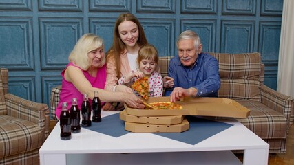 Happy multigenerational family having lunch party at home, eating pizza food, raising toast together