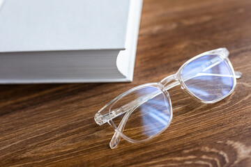 Fototapeta na wymiar Close up eyesglasses on books at table at home. Desk work at home.