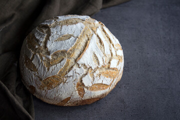 Fresh baked artisan bread on a table. Dark gray background with copy space. Homemade sourdough bread recipe. 