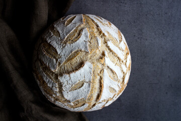 Fresh baked artisan bread on a table. Dark gray background with copy space. Homemade sourdough bread recipe. 