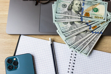 Dollar banknotes, mobile phone, glasses and pen on the keyboard, making money on the Internet,...