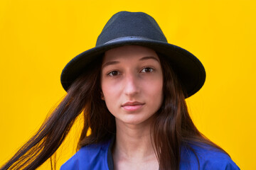 Close-up portrait of young girl on yellow background