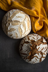 Two round freshly baked breads on yellow linen fabric background. Artisan bread top view photo. 