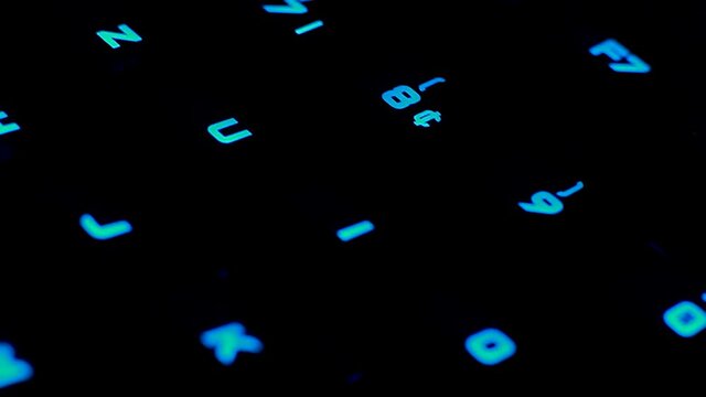 close-up tracking shot of a gaming keyboard and office and study letters in contrast with blue LEDs