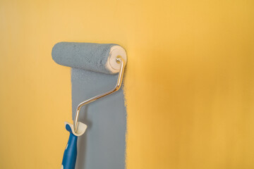 Obraz premium Paint Roller with Blue Paint on a Yellow Wall