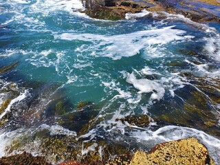 Waves crashing over rocks on sunny blue sky day, Austimere Beach, NSW, Australia
