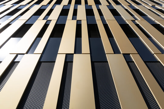 Abstract house facade with gold-coloured and black pattern with sun reflection as background for architecture or art