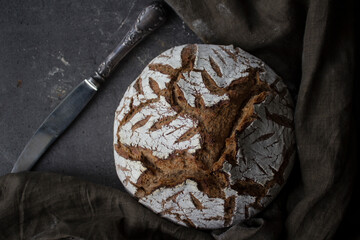 Fresh baked artisan bread on a table. Dark gray background with copy space. Homemade sourdough bread recipe. 