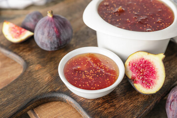 Bowls of sweet fig jam on wooden table, closeup