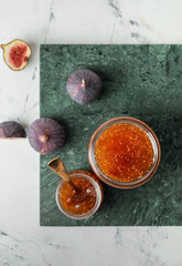 Jars of sweet fig jam on white table