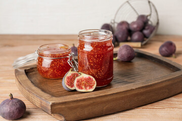 Jars of sweet fig jam on wooden table