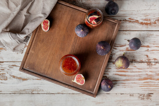 Jars of sweet fig jam on wooden table