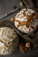 Still life with beautifully scored artisan bread on a table. Dark green linen fabric, white and rye sourdough bread and dried fruits top view photo. healthy ting concept. 