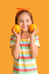 Fototapeta na wymiar Funny little girl with oranges on color background