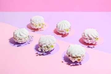 Tasty marshmallows with flowers on color background