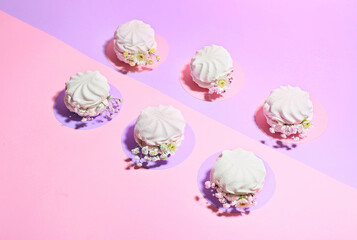 Tasty marshmallows with flowers on color background