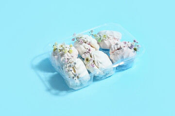Tasty marshmallows with flowers on color background