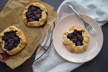 Freshly baked blackberry galettes--two on a cooling rack, one on a plate.
.