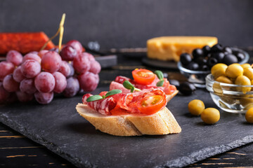Tasty sandwiches with salami on dark wooden background