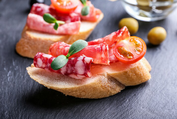 Tasty sandwiches with salami on dark background, closeup