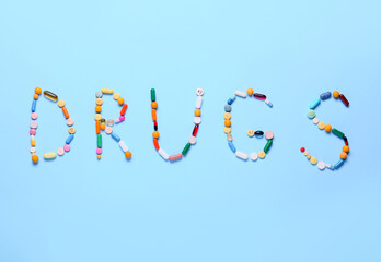 Word DRUGS made of different pills on color background. Addiction concept