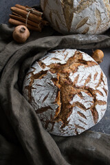 Tasty bread close up photo. Round sourdough bread with beautiful pattern on the top. Linen fabric towel on background. Homemade bread on a table. 