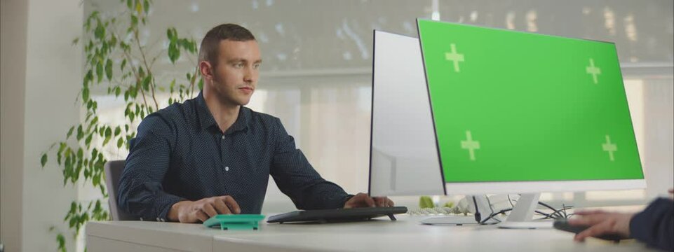 Mock-up greenscreen computer monitor on office table. Close-up manager working by personal computer in a modern office.