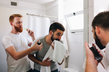 Obraz premium Young male couple using perfume and towel in bathroom in the morning