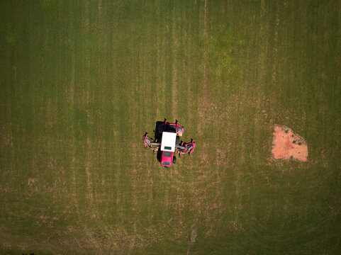 Drone image of large red lawn mower working on suburban baseball fields in Glenmore Park, NSW, Australia