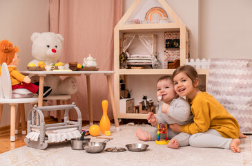 Brother and sister playing together. Cute toddler girl and funny baby boy in nursery room. Two...
