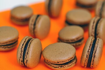 Homemade Chocolate cocoa macaron cookies filled with chocolate hazelnut ganache on an orange background