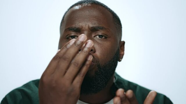 Closeup african man throwing air kiss from hand in grey background in studio.