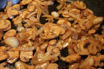 Close-up of sautéed mushrooms and onions in a cast iron skillet.