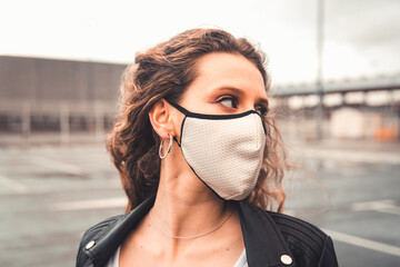 Young sexy woman with a white mask on a parking lot